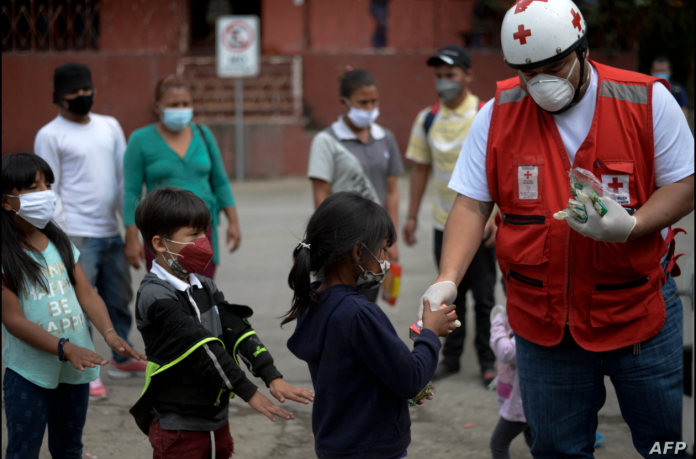 Un voluntario de la Cruz Roja entrega alimentos a los niños migrantes hondureños que regresan a Honduras en El Florido, Chiquimula, Guatemala el 19 de enero de 2021, en la frontera con Honduras.