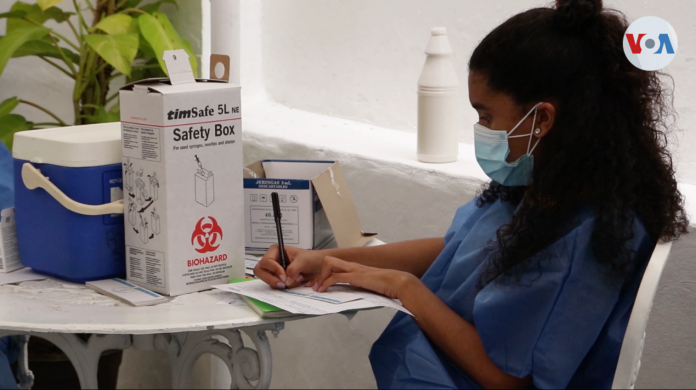 Una trabajadora de salud anota los datos de los pacientes en un centro de vacunación en Caracas, Venezuela. Imagen tomada de video, domingo 11 de abril de 2021.