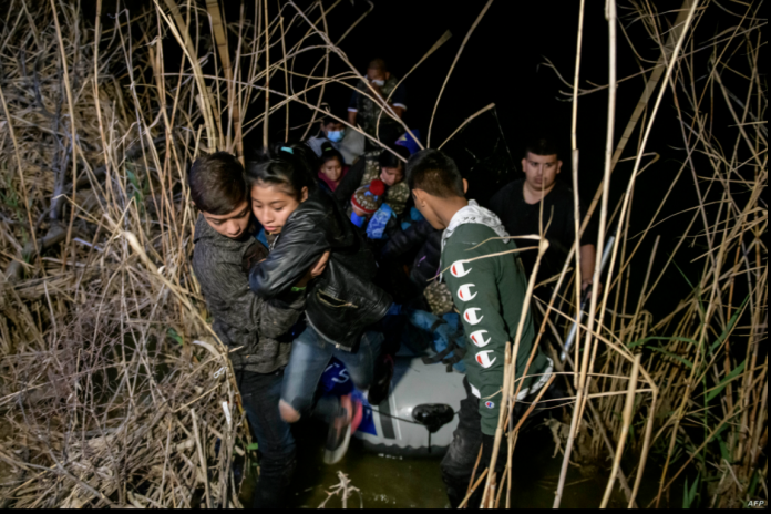 Inmigrantes de Honduras y Guatemala que llegan ilegalmente desde México desembarcan de un bote inflable en el lado estadounidense del río Grande antes de solicitar asilo y entregarse a los agentes de la patrulla fronteriza, el 28 de marzo de 2021.