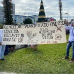 Dos salvadoreños del movimiento antivacunas posan una pancarta expresando estar en contra del fármaco COVID-19. Foto: YSKL.