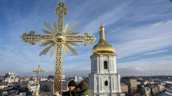 Dos hombres instalan una cruz restaurada en la cúpula de la Catedral de Santa Sofía en Kiev, Ucrania, el 21 de diciembre de 2023. Foto: AP.