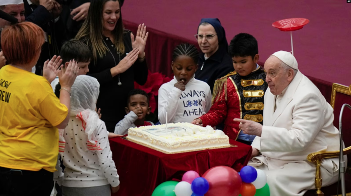 El papa Francisco celebra sus 87 años frente a un pastel y un grupo de niños durante una audiencia en el Vaticano el 17 de diciembre de 2023. Foto: Cortesía.