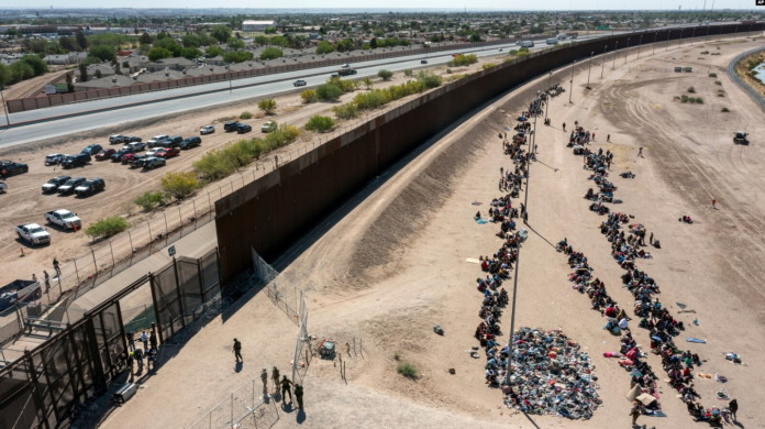 ARCHIVO - Migrantes forman filas frente a la valla en la frontera de EEUU con México a la espera de ser transportados a una instalación de la Patrulla Fronteriza, el 10 de mayo de 2023, en El Paso, Texas. (AP Foto/Andrés Leighton)