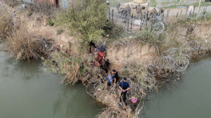 Un grupo de migrantes intenta atravesar una valla de alambre a orillas del río Grande mientras miembros de la Guardia Nacional de EEUU hacen guardia al otro lado de la valla en Eagle Pass, Texas, Estados Unidos, el 27 de febrero de 2024. Foto: Cortesía.