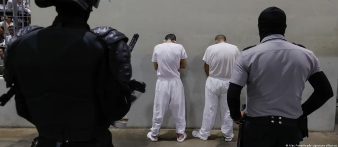 Elementos de seguridad observan a dos personas detenidas en un centro penitenciario de El Salvador. Foto: Cortesía.