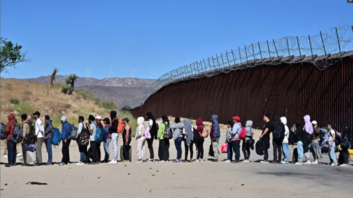 Migrantes esperan en fila con la esperanza de ser procesados ​​por los agentes de Aduanas y Patrulla Fronteriza después de llegar a Jacumba Hot Springs, California, luego de caminar bajo un intenso calor desde México a Estados Unidos, 5 de junio de 2024. Foto: Cortesía.