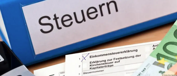 Un archivador con la inscripción Steuern (impuestos), junto a una calculadora, unos billetes y el impreso de la declaración de la renta alemana. Imagen de referencia.