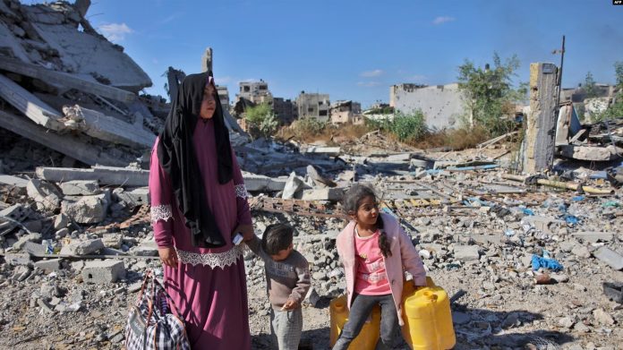 Una mujer palestina junto a sus hijos en la carretera de Salah al-Din, en el este de Gaza, después de ser obligada a huir de las operaciones militares israelíes en Beit Lahia, norte de la franja de Gaza, el 22 de octubre de 2024, en medio de la guerra entre Israel y Hamás.