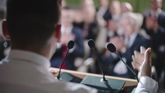 Primer plano de perfil de un político hablando a los micrófonos en una convención política. Imagen de referencia. Foto: Cortesía.